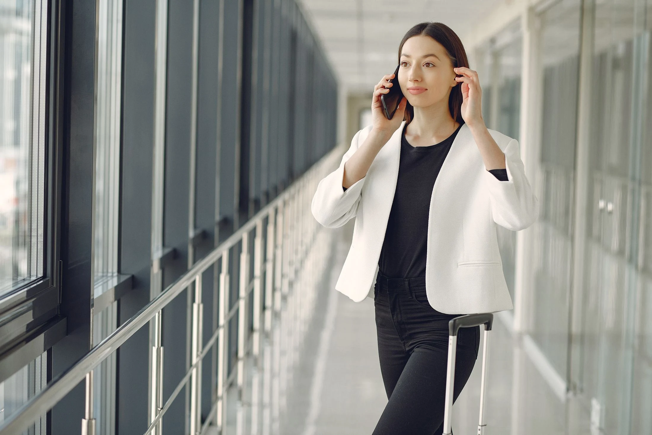 Business traveller speaking on a phone in an airport corridor